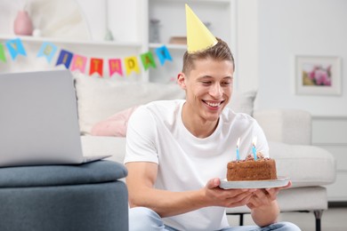 Photo of Man with cake celebrating his birthday and having video call via laptop at home