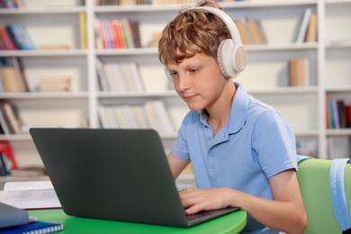 Photo of Student with laptop studying at table in library