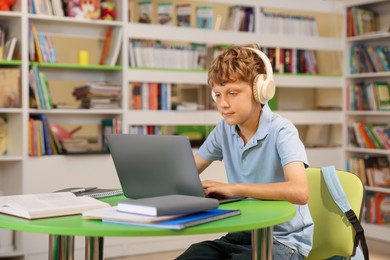 Photo of Student with laptop studying at table in library