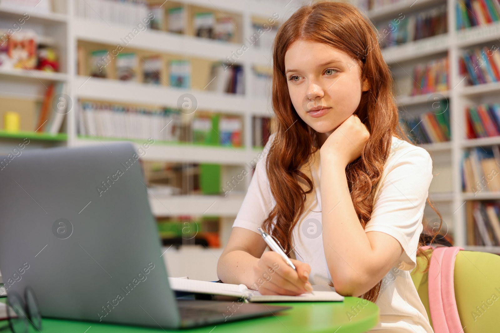 Student with laptop studying at table in library Photo of Student with laptop studying at table in library