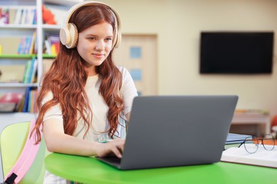 Photo of Student with laptop studying at table in library