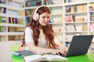 Photo of Student with laptop studying at table in library