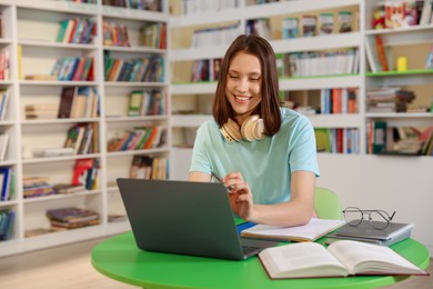 Photo of Student with laptop studying at table in library. Space for text