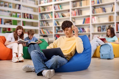 Photo of Student with laptop studying on bean bag in library