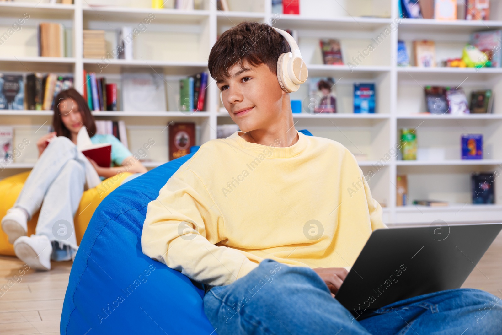 Student with laptop studying on bean bag in library Photo of Student with laptop studying on bean bag in library