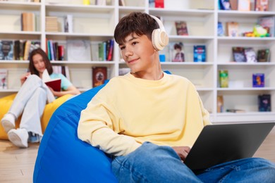 Photo of Student with laptop studying on bean bag in library