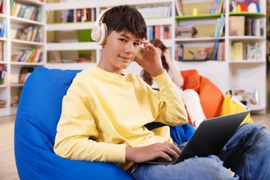 Photo of Student with laptop studying on bean bag in library