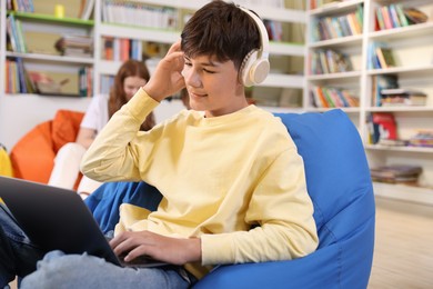 Photo of Student with laptop studying on bean bag in library