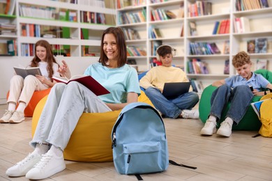 Photo of Student with book studying on bean bag in library