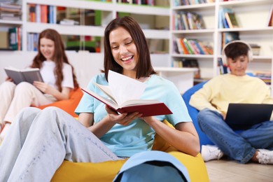 Photo of Student with book studying on bean bag in library