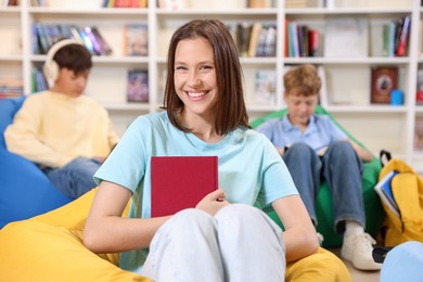 Photo of Student with book studying on bean bag in library