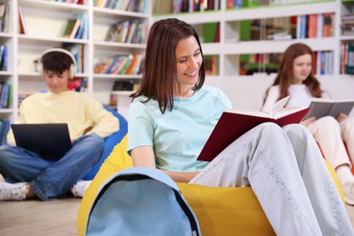 Photo of Student with book studying on bean bag in library