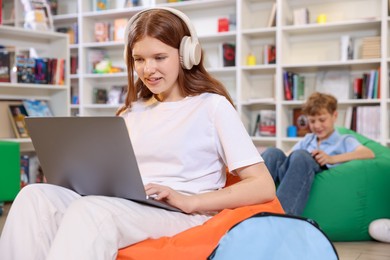 Photo of Student with laptop studying on bean bag in library