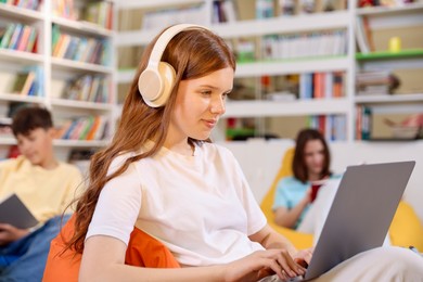 Photo of Student with laptop studying on bean bag in library