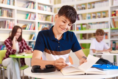 Photo of Student with books studying at table in library