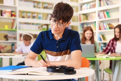 Photo of Student with books studying at table in library