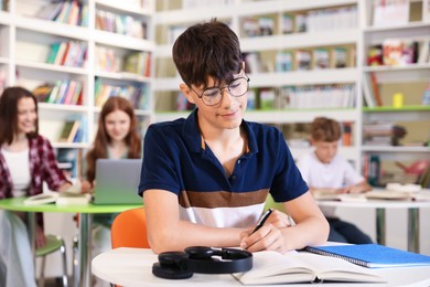 Photo of Student with books studying at table in library