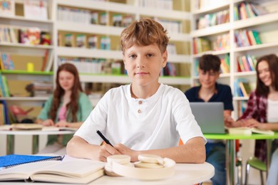 Photo of Student with books studying at table in library