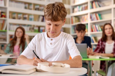 Photo of Student with books studying at table in library