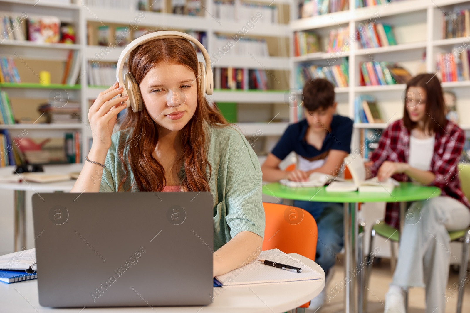 Student with laptop studying at table in library Photo of Student with laptop studying at table in library