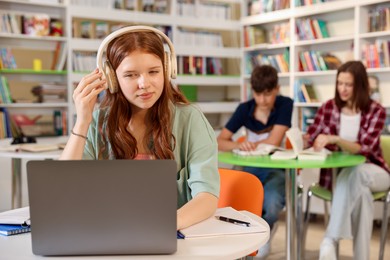 Photo of Student with laptop studying at table in library