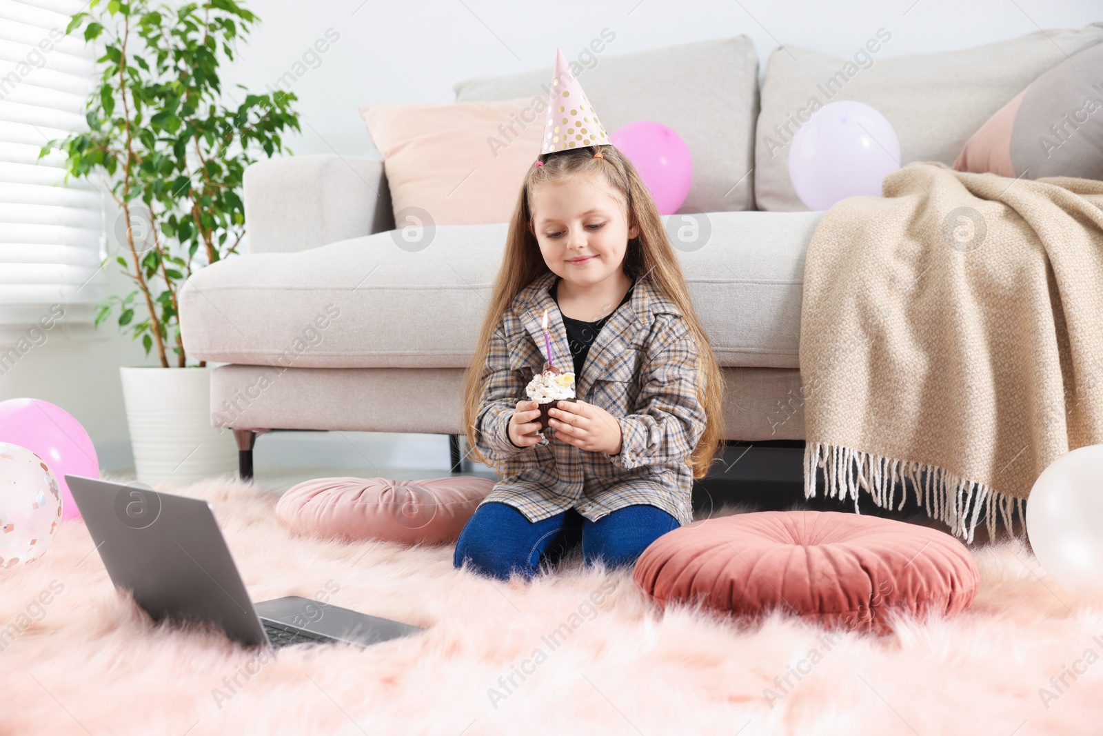 Birthday celebration. Little girl with cupcake having video call via laptop at home Photo of Birthday celebration. Little girl with cupcake having video call via laptop at home