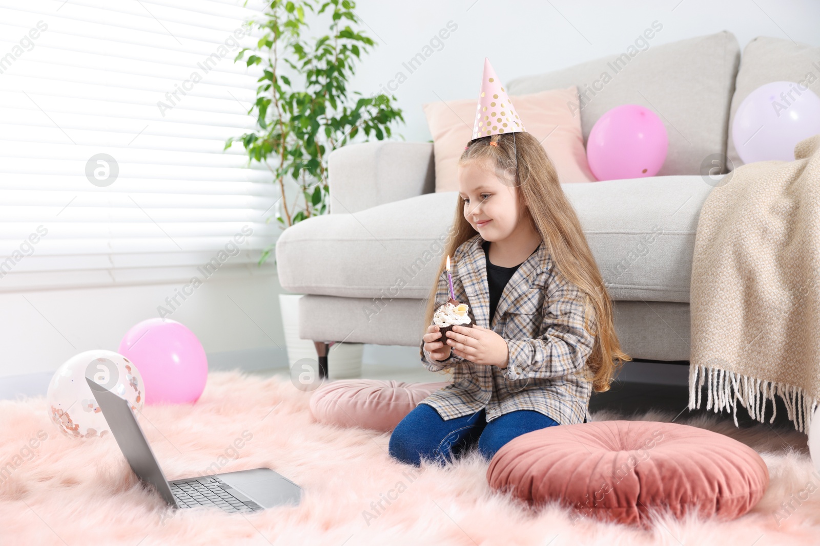 Birthday celebration. Little girl with cupcake having video call via laptop at home Photo of Birthday celebration. Little girl with cupcake having video call via laptop at home