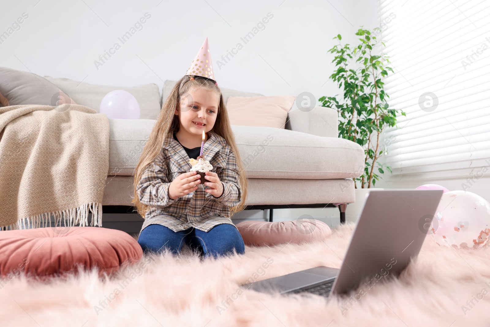 Birthday celebration. Little girl with cupcake having video call via laptop at home Photo of Birthday celebration. Little girl with cupcake having video call via laptop at home