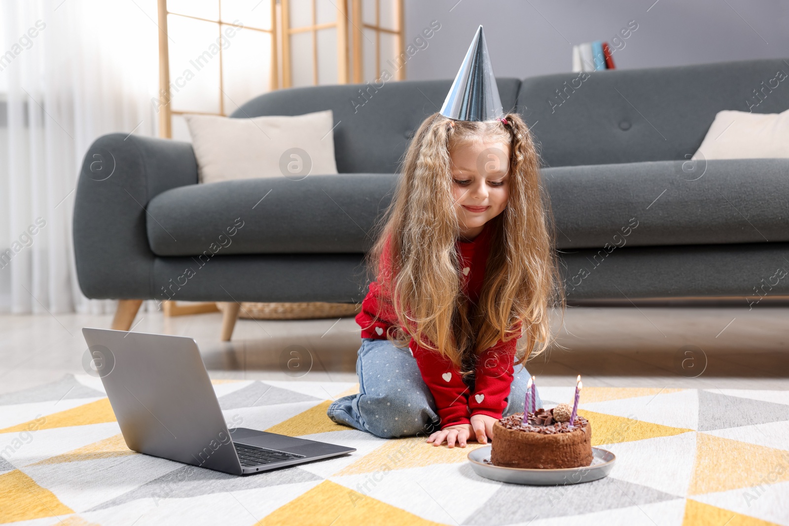 Birthday celebration. Little girl with cake having video call via laptop at home Photo of Birthday celebration. Little girl with cake having video call via laptop at home
