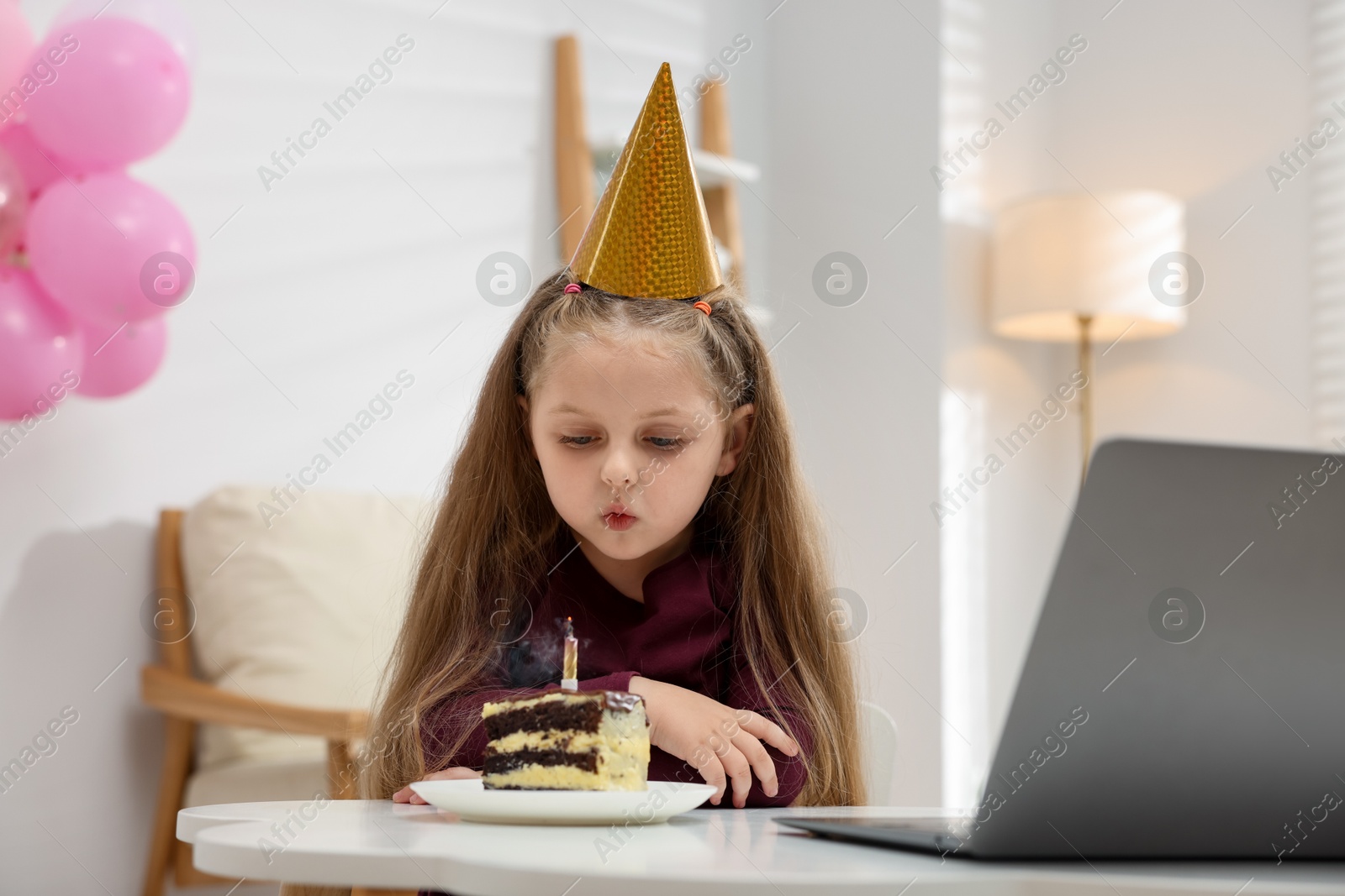 Birthday celebration. Little girl with piece of cake having video call via laptop at table indoors Photo of Birthday celebration. Little girl with piece of cake having video call via laptop at table indoors