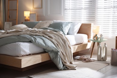 Photo of Comfortable bed with soft linens, lamp and decor in stylish room. Home textile