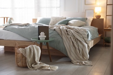 Photo of Comfortable bed with soft linens, lamp and decor in stylish room. Home textile