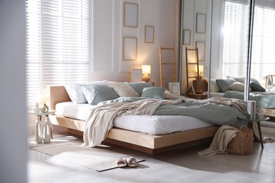 Photo of Comfortable bed with soft linens, lamp and decor in stylish room. Home textile