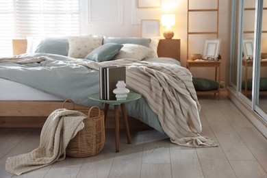 Photo of Comfortable bed with soft linens, lamp and decor in stylish room. Home textile