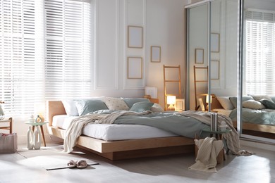 Photo of Comfortable bed with soft linens, lamp and decor in stylish room. Home textile