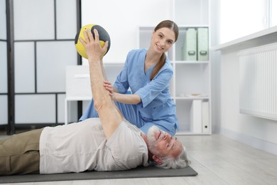 Photo of Doctor and patient exercising with medicine ball in clinic