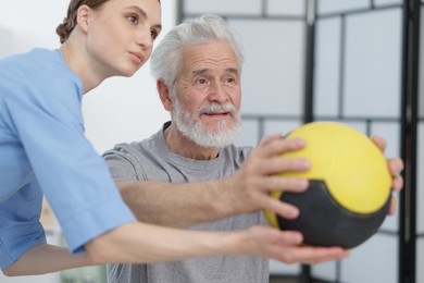 Photo of Doctor and patient exercising with medicine ball in clinic