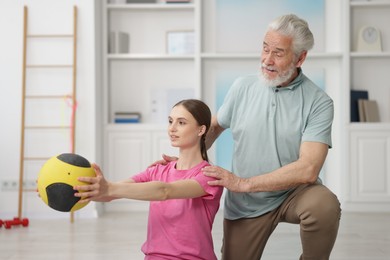 Photo of Doctor and patient exercising with medicine ball in clinic