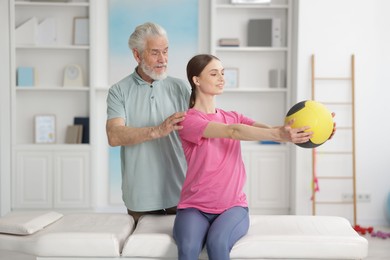 Photo of Doctor and patient exercising with medicine ball in clinic