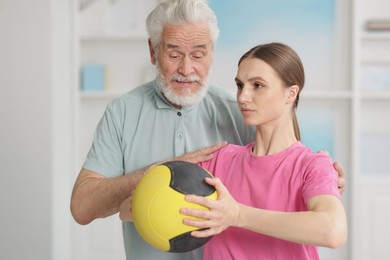 Photo of Doctor and patient exercising with medicine ball in clinic
