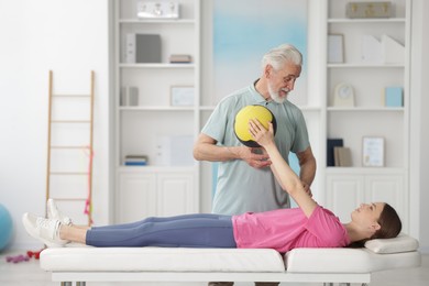 Photo of Doctor and patient exercising with medicine ball in clinic