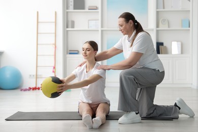 Photo of Doctor and patient exercising with medicine ball in clinic