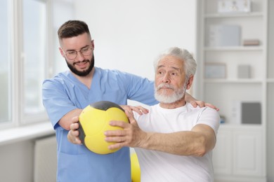 Photo of Doctor and patient exercising with medicine ball in clinic