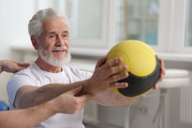 Photo of Doctor and patient exercising with medicine ball in clinic