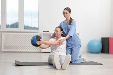 Photo of Doctor and patient exercising with medicine ball in clinic