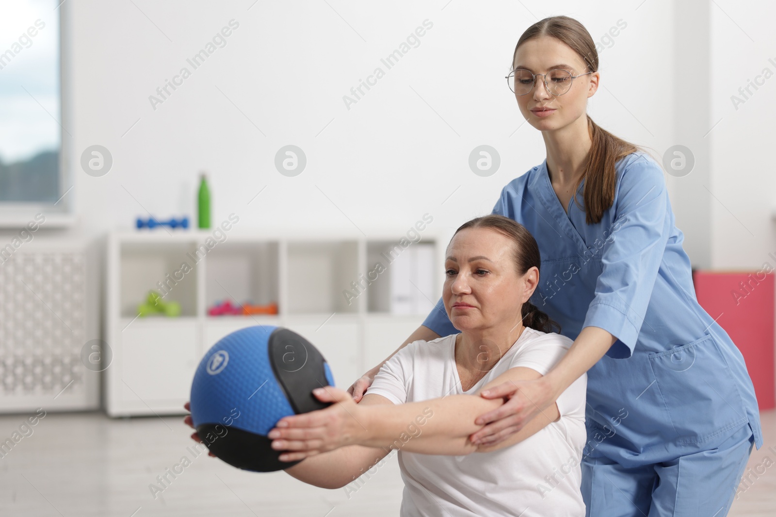 Doctor and patient exercising with medicine ball in clinic, space for text Photo of Doctor and patient exercising with medicine ball in clinic, space for text