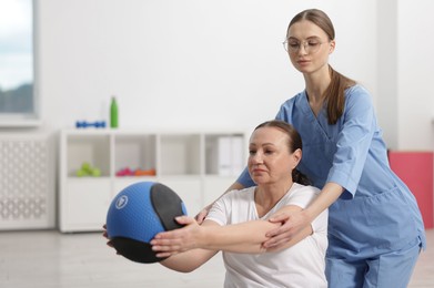 Photo of Doctor and patient exercising with medicine ball in clinic, space for text