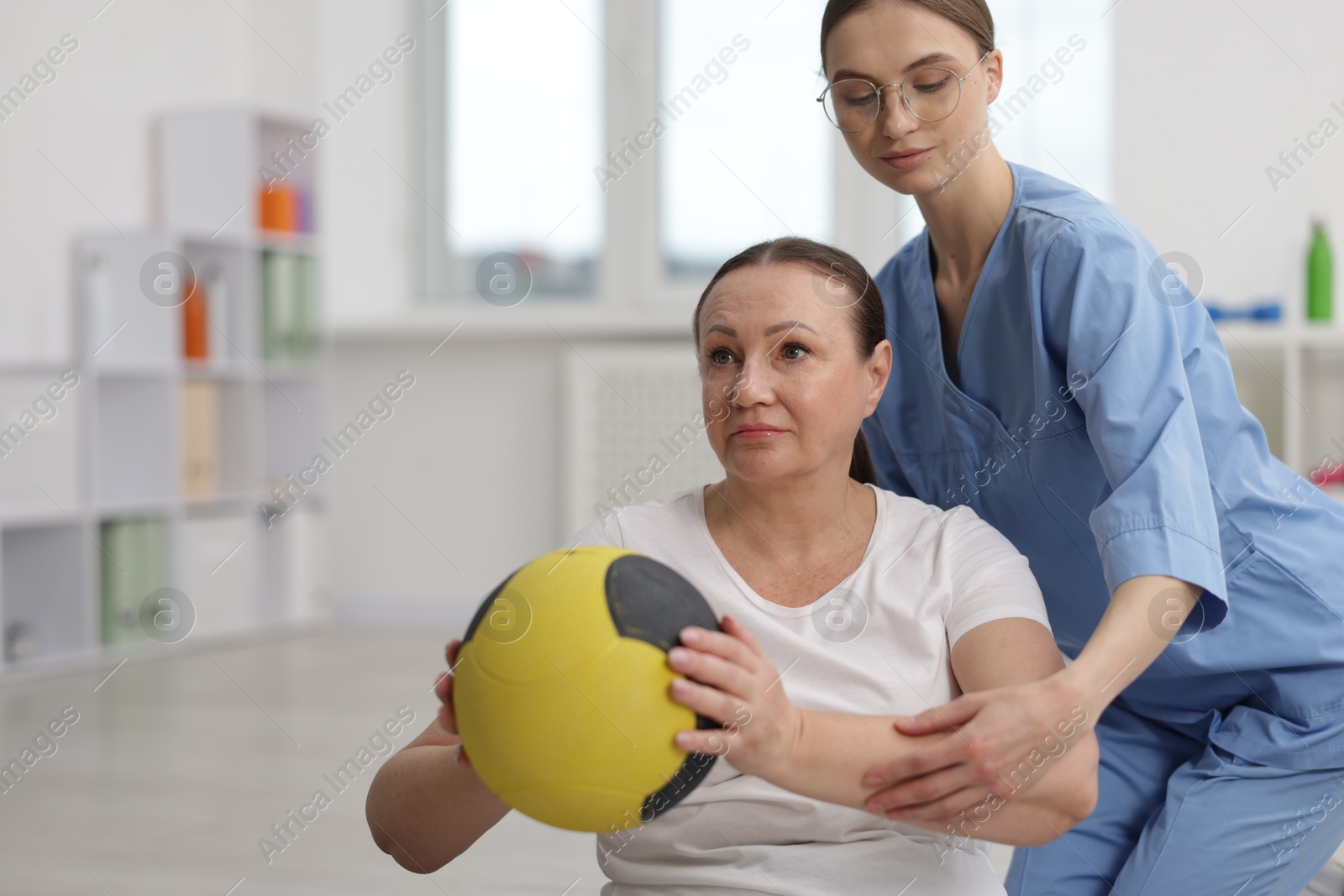 Doctor and patient exercising with medicine ball in clinic, space for text Photo of Doctor and patient exercising with medicine ball in clinic, space for text