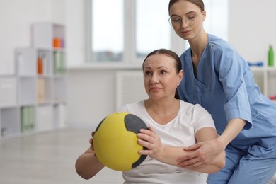 Photo of Doctor and patient exercising with medicine ball in clinic, space for text