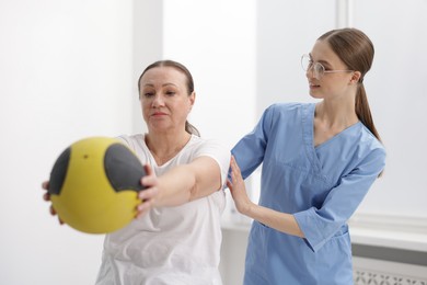 Photo of Doctor and patient exercising with medicine ball in clinic